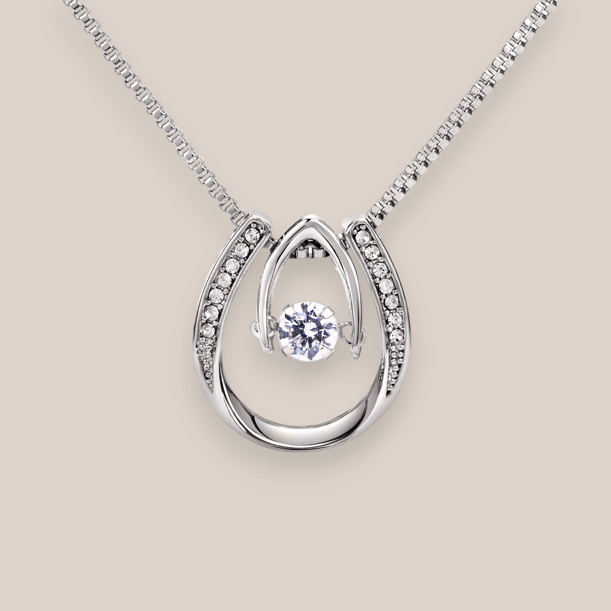 14k white gold-plated Abundance necklace featuring a round-cut cubic zirconia crystal suspended inside a dainty curved pendant with embedded crystals.