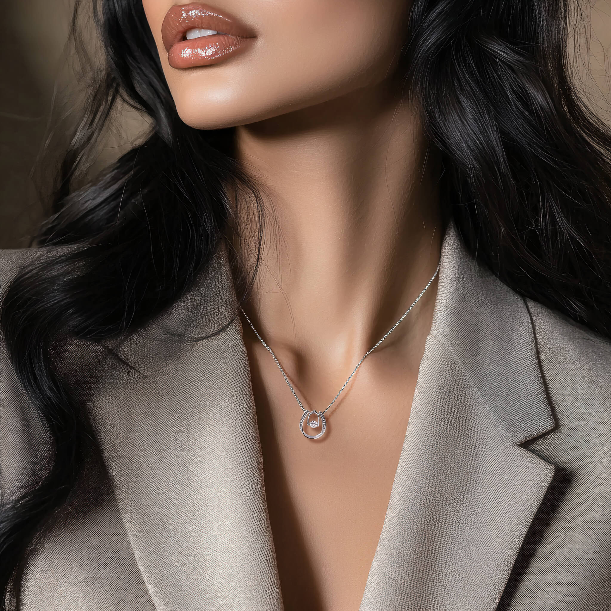 Model wearing the Abundance necklace with a light gray blazer. The pendant rests just below her collarbone.