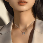 Model wearing the Abundance necklace with a beige blazer in soft, natural light, showcasing the shimmering pendant and chain.