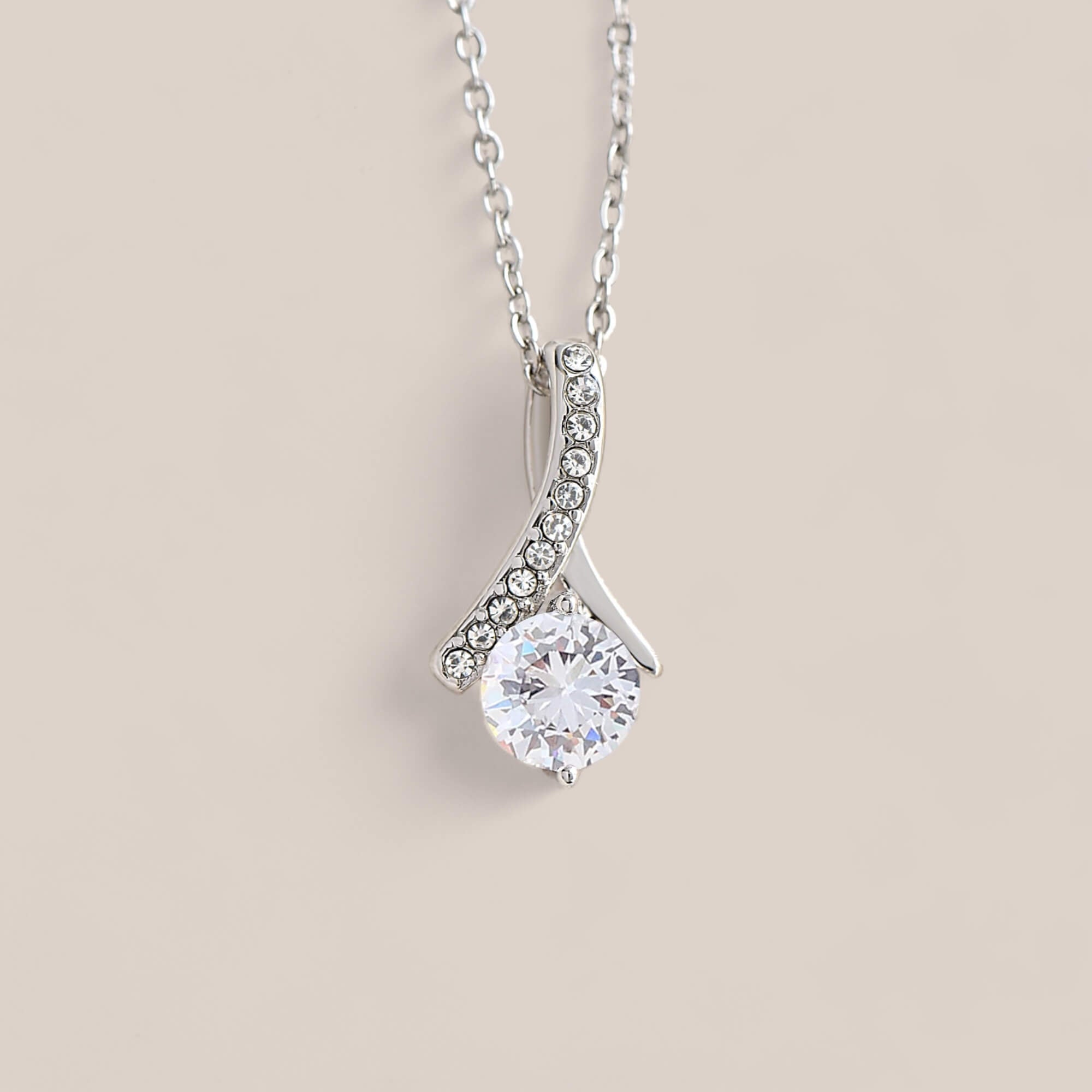 14k white gold-plated Allure necklace featuring a round-cut cubic zirconia crystal suspended from a dainty ribbon-shaped pendant with tiny crystals embedded along one side.