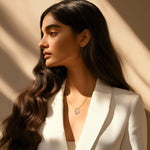 Model wearing the Passion necklace in 18k gold finish with sunlight beaming in from the top left. The pendant rests a few inches below her collarbone.