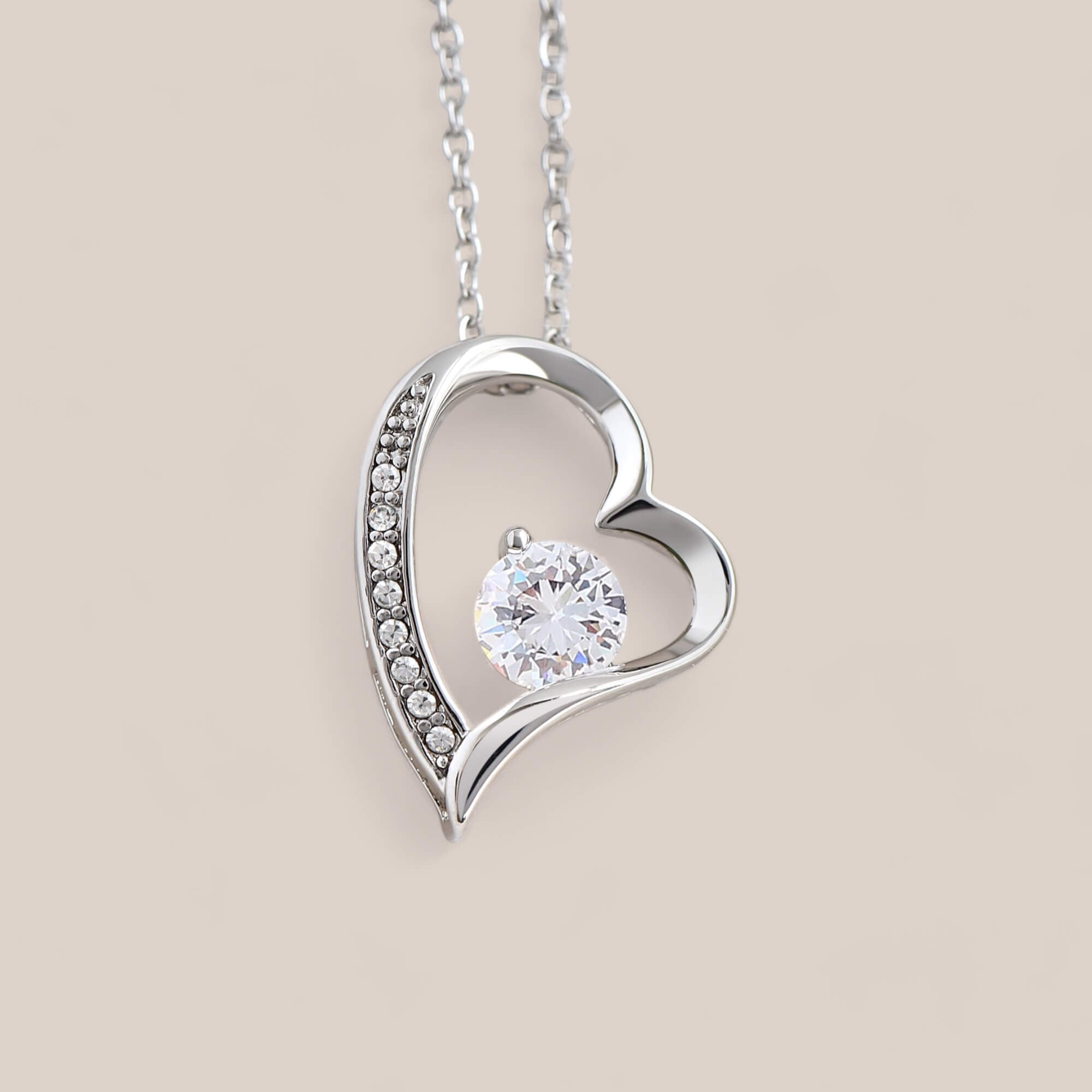 14k white gold-plated Passion necklace featuring an asymmetrical heart-shaped design with embedded crystals along the side of the heart and a round-cut cubic zirconia crystal in the center.