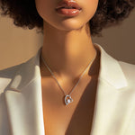 Model wearing the Passion necklace in 14k white gold finish with a white blazer in natural sunlight, highlighting the shimmering chain and pendant.