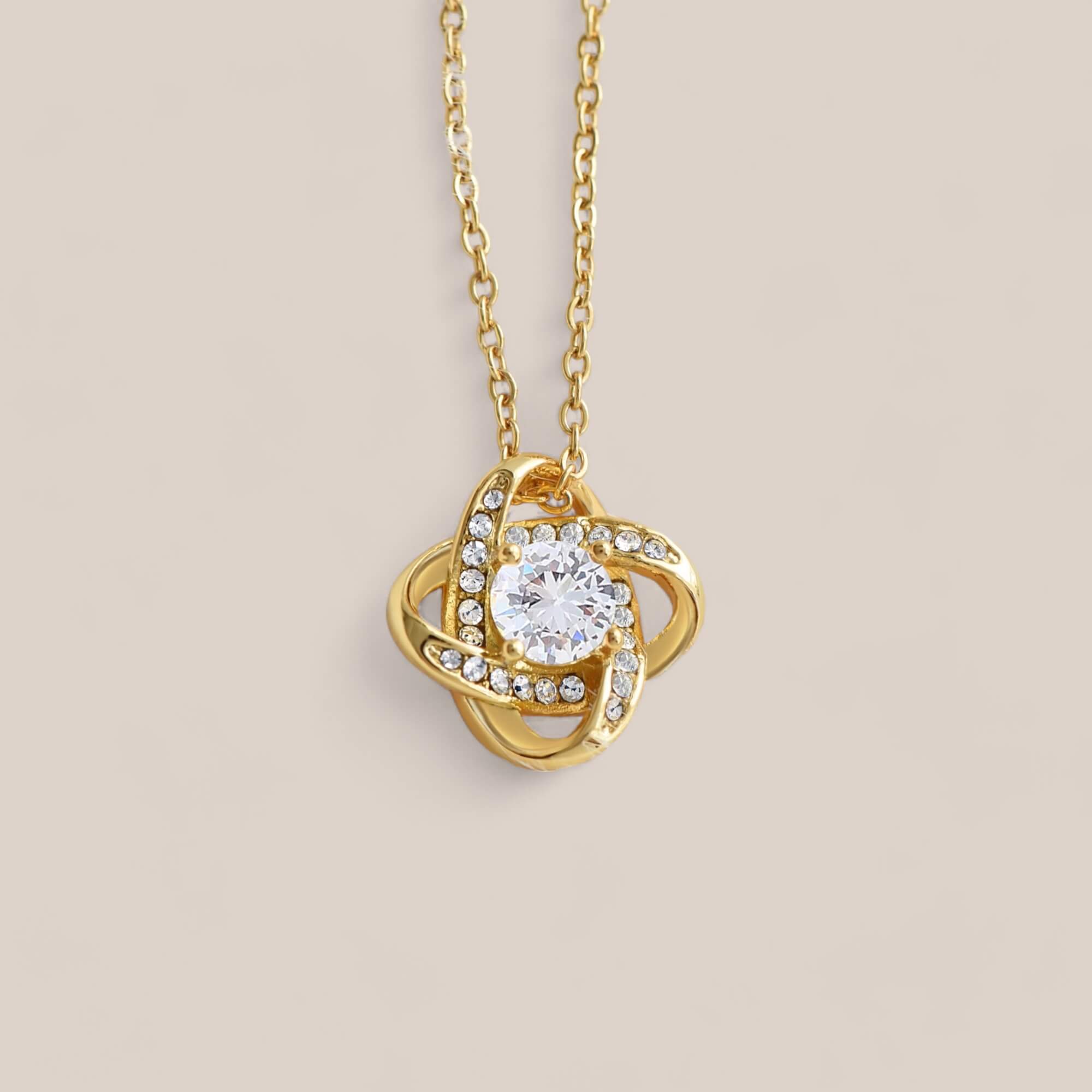 18k gold-plated Radiance necklace featuring a round-cut cubic zirconia crystal surrounded by intertwining loops that resemble a Celtic knot with embedded crystals.