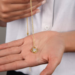 Model dangling Radiance necklace in 18k gold finish over the palm of her hand, highlighting the pendant's dainty size.