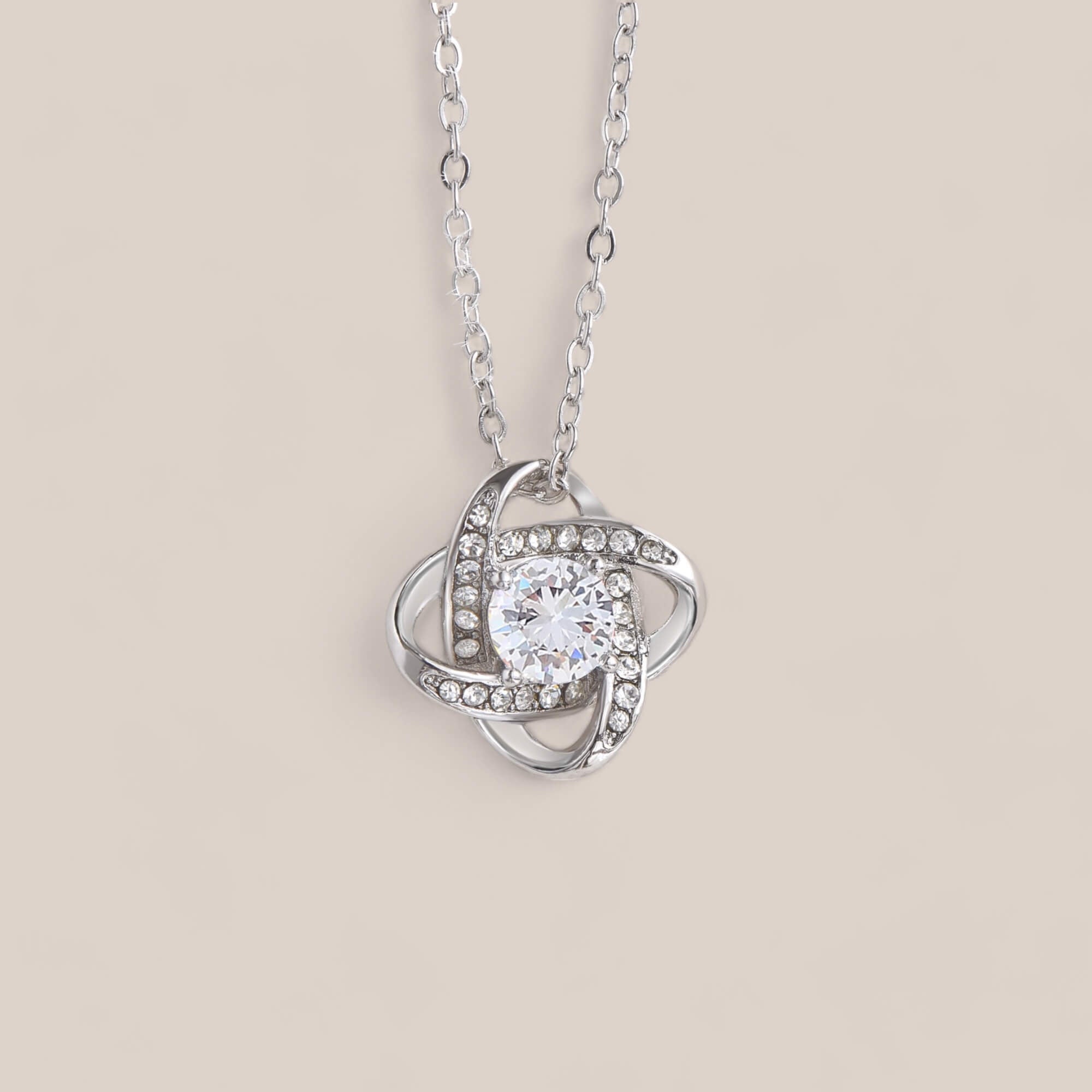 14k white gold-plated Radiance necklace featuring a round-cut cubic zirconia crystal surrounded by intertwining loops that resemble a Celtic knot with embedded crystals.